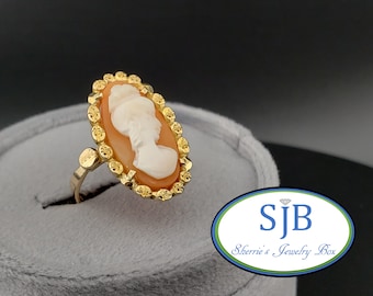Op de afbeelding: Een gouden ring met een cameo met het profiel van een vrouw in een witte cameo, gezet in een ovaal gouden frame.