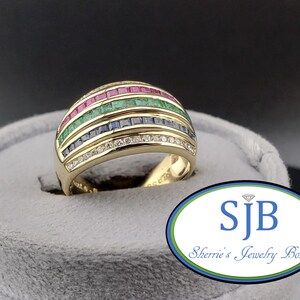 Peut inclure: Une bague en or avec quatre rangées horizontales de pierres précieuses serties en rail. La rangée supérieure contient des rubis rouges, la deuxième des émeraudes vertes, la troisième des saphirs bleus et la rangée inférieure des diamants blancs.