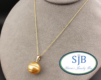 May include: A gold chain necklace with a golden pearl pendant. The pearl is round and has a smooth surface. The necklace is on a gray background. The text "SJB Sherrie's Jewelry Box" is visible in the lower right corner of the image.