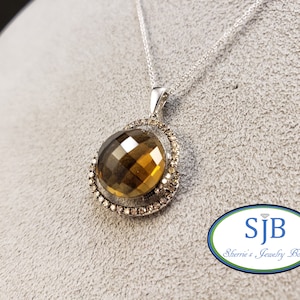 May include: A silver chain necklace with a brown gemstone pendant surrounded by a halo of smaller diamonds.