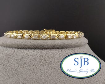 May include: A gold tennis bracelet with a row of round, pear-shaped, and baguette diamonds.