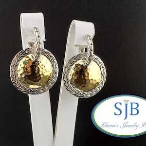 Pode incluir: Brincos prateados e dourados com um centro dourado martelado e uma borda prateada em forma de corda. Os brincos são exibidos em suportes brancos sobre um fundo preto. De Sherrie's Jewelry Box.