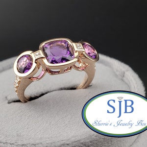 May include: A rose gold ring featuring three amethyst stones and a single diamond. The ring is set in a delicate, intricate design.