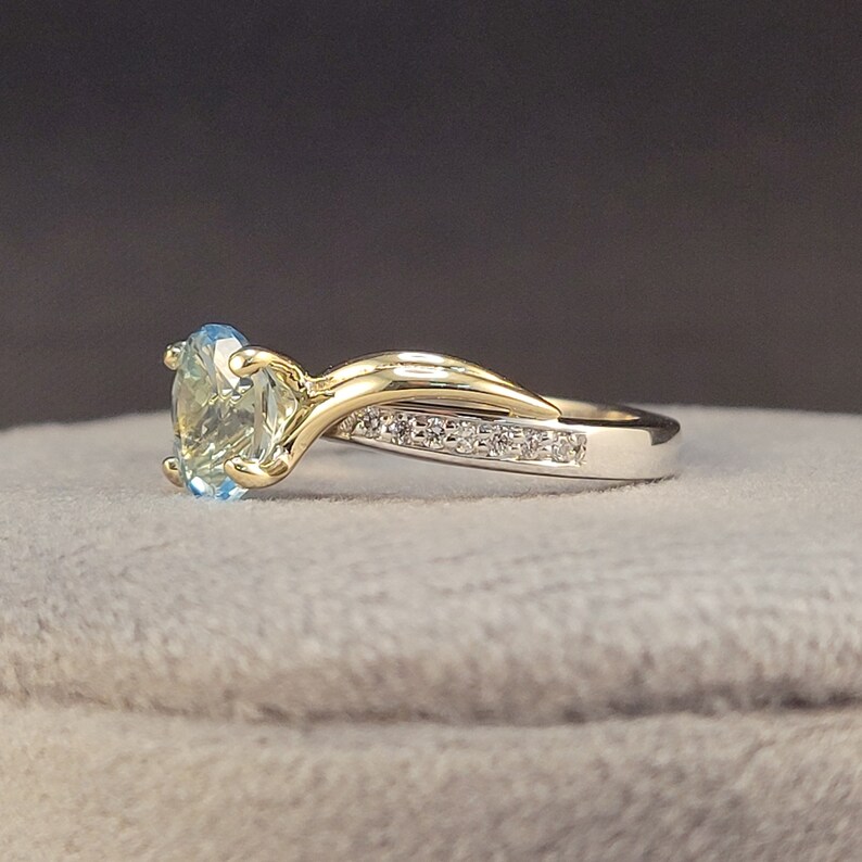 May include: A gold and silver ring with a light blue gemstone and a row of small diamonds.
