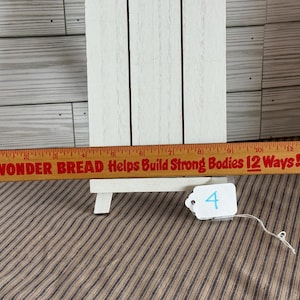 May include: A vintage wooden ruler with red text reading "WONDER BREAD Helps Build Strong Bodies 12 Ways!" The ruler is in front of a white wooden easel. A small white tag with the number "4" is attached.
