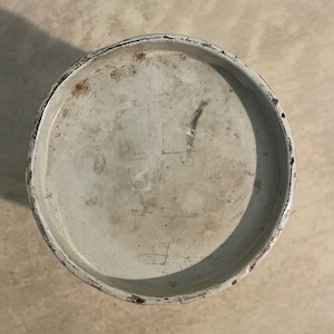 May include: White metal lid with a black rim. The lid has some scratches and marks on the surface.