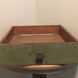 May include: A vintage wooden drawer with a green painted finish and a round knob. The drawer is empty and has a worn, rustic look.