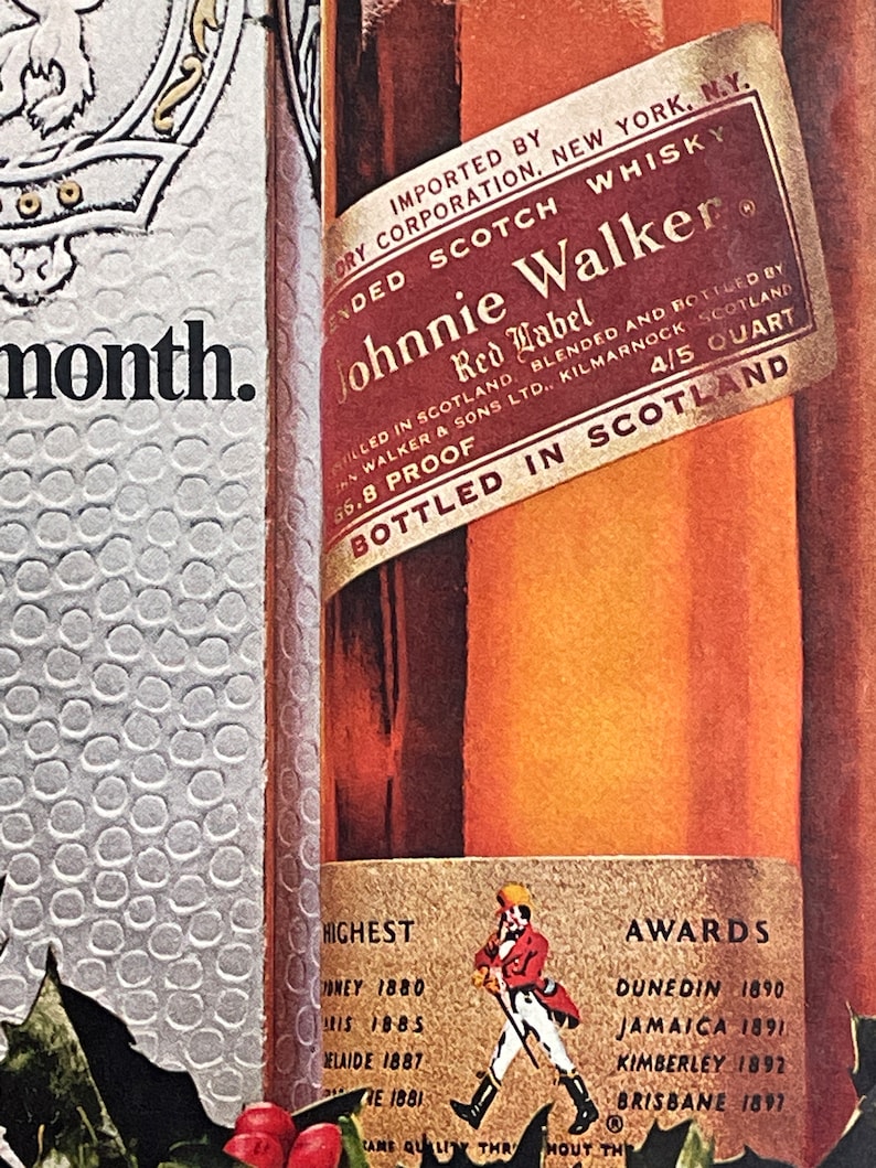 May include: A close-up of a Johnnie Walker Red Label Scotch Whisky bottle with a gold label. The label features the Johnnie Walker logo, the words "Red Label" and "Blended Scotch Whisky", and the text "Bottled in Scotland". The bottle is surrounded by a festive holiday background.