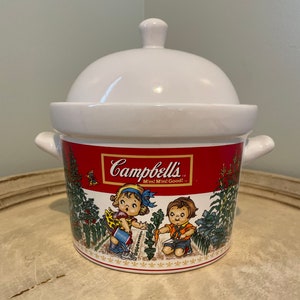 May include: White ceramic soup tureen with a red lid and a red band around the bottom. The tureen features a colorful illustration of two children in a garden with the text "Campbell's M'm! M'm! Good!"