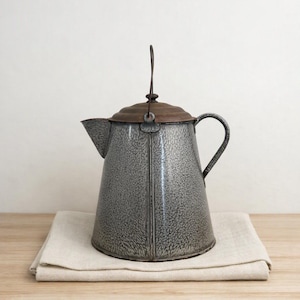 May include: A gray speckled enamel coffee pot with a wide base, a tapered body, and a curved handle. The pot features a dark brown metal lid with a vertical wire bail handle attached to the top. The surface has a textured, mottled finish.