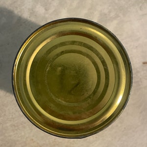 May include: The top of a gold metal can with a slightly dented rim.