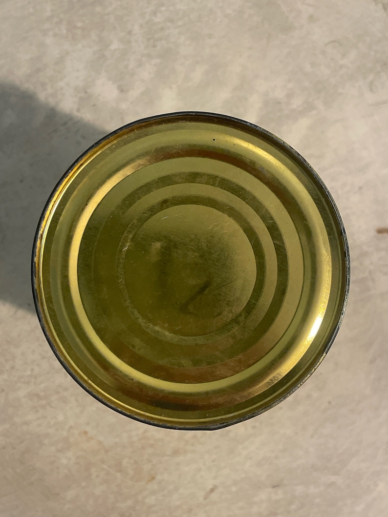 May include: The top of a gold metal can with a slightly dented rim.