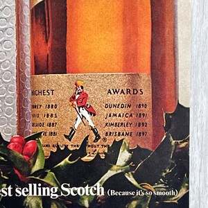 May include: A vintage advertisement for a bottle of Scotch whisky. The bottle is labeled with the brand name and the words "Bottled in Scotland". The ad also features a red-clad figure walking with a staff, and a list of awards won by the whisky. The text at the bottom of the ad reads "Highest selling Scotch (Because it's so smooth)".