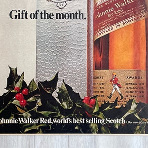 May include: A bottle of Johnnie Walker Red Label Scotch whisky with a red and gold label. The bottle is surrounded by holly and berries. The text on the label reads "Johnnie Walker Red Label, world's best selling Scotch (Because it's so smooth)".