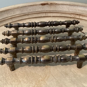 May include: Set of six antique brass cabinet knobs with a decorative, fluted design. The knobs have a slightly tarnished finish, giving them a vintage look.