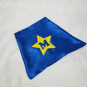 May include: Blue satin cape with a yellow star and the letter "M" in the center.
