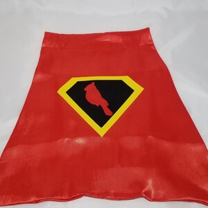 May include: Red satin cape with a yellow and black diamond-shaped emblem featuring a red cardinal silhouette.