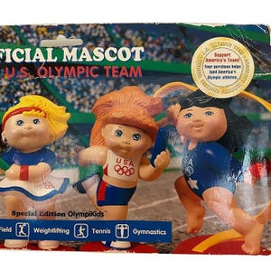 May include: A vintage package of Special Edition OlympiKids, the official mascot of the U.S. Olympic Team. The package features three doll figures in athletic poses, wearing red, white, and blue outfits. The text on the package reads "Support America's Team!"