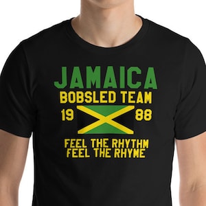 Puede incluir: Camiseta negra con el texto "Jamaica Bobsled Team 1988" y un gráfico de bandera jamaicana. El texto debajo de la bandera dice "Feel the Rhythm Feel the Rhyme".