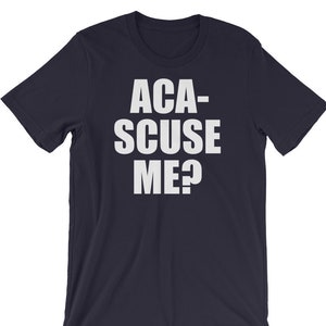 May include: Navy blue t-shirt with the text "ACA-SCUSE ME?" in bold white letters. The shirt has short sleeves and a crew neck. The text is centered on the front of the shirt.