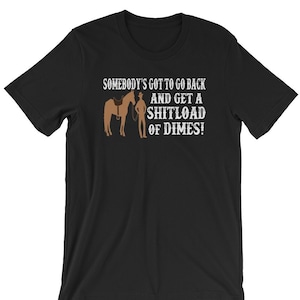 Può includere: Maglietta nera con una grafica bianca di un cowboy a cavallo. Il testo sulla grafica dice "Somebody's got to go back and get a shitload of dimes!"