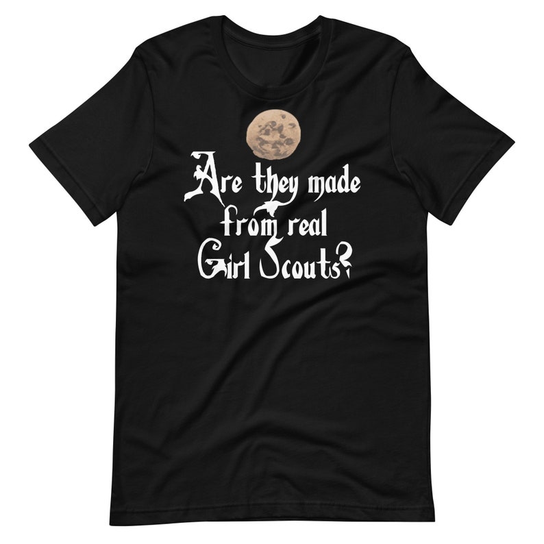 May include: Black t-shirt with a white graphic of a moon and the text "Are they made from real Girl Scouts?"
