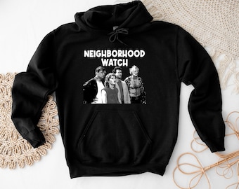 Puede incluir: Sudadera con capucha negra con el texto "Neighborhood Watch" en letras blancas. La imagen presenta una foto en blanco y negro de cuatro personas.