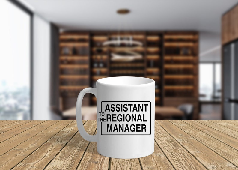May include: White ceramic coffee mug with a black border around the text "Assistant to the Regional Manager".