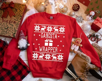 May include: Red Christmas sweater with a white snowflake pattern and the text "Gangsta Wrapper".