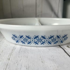 May include: White divided baking dish with a blue floral pattern around the rim.