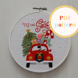 May include: Embroidered hoop art featuring a red vintage car with a Christmas tree, presents, and candy canes on top. The text "'Tis the Season" is stitched above the car.