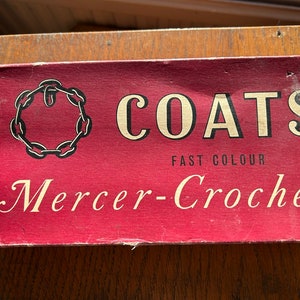May include: A red label with the text "COATS FAST COLOUR Mercer-Crochet" and a chain link design.