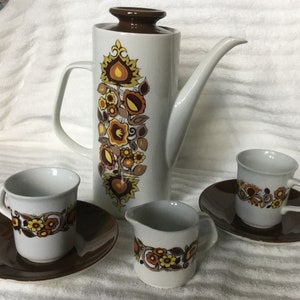 May include: A vintage coffee set with a brown and white floral design. The set includes a coffee pot, a creamer, two cups, and two saucers.