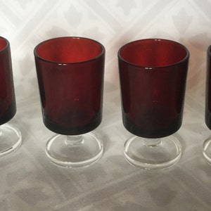 May include: Set of four red glass shot glasses with clear glass stems and bases.