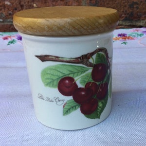 May include: White ceramic jar with a wooden lid, featuring a hand-painted illustration of red cherries on a branch with green leaves. The jar has the text "Late Duke Cherry" printed on the front.
