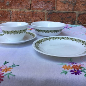 Puede incluir: Un juego de vajilla Corelle blanca con un patrón floral verde. El juego incluye un tazón pequeño, un tazón grande y un plato.