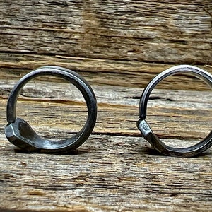 May include: Two silver metal rings with a unique hammered finish. The rings are simple and modern in design.