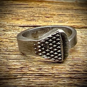 May include: A silver ring made from a repurposed horseshoe nail. The ring has a textured, diamond-shaped pattern on the top.