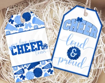 Puede incluir: Dos etiquetas de regalo azules y blancas con temas de porristas. Una etiqueta dice "We love our cheer team" con pompones azules y un megáfono. La otra etiqueta dice "Cheer loud & proud" con un pompón azul.