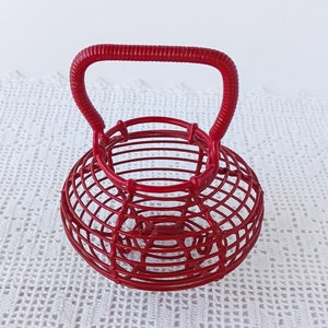 May include: A red wire basket with a handle. The basket is made of thin wire and has a round shape.