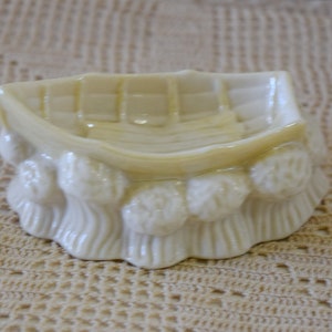 May include: A white ceramic trinket dish shaped like a boat with a row of small white ceramic mushrooms around the rim.