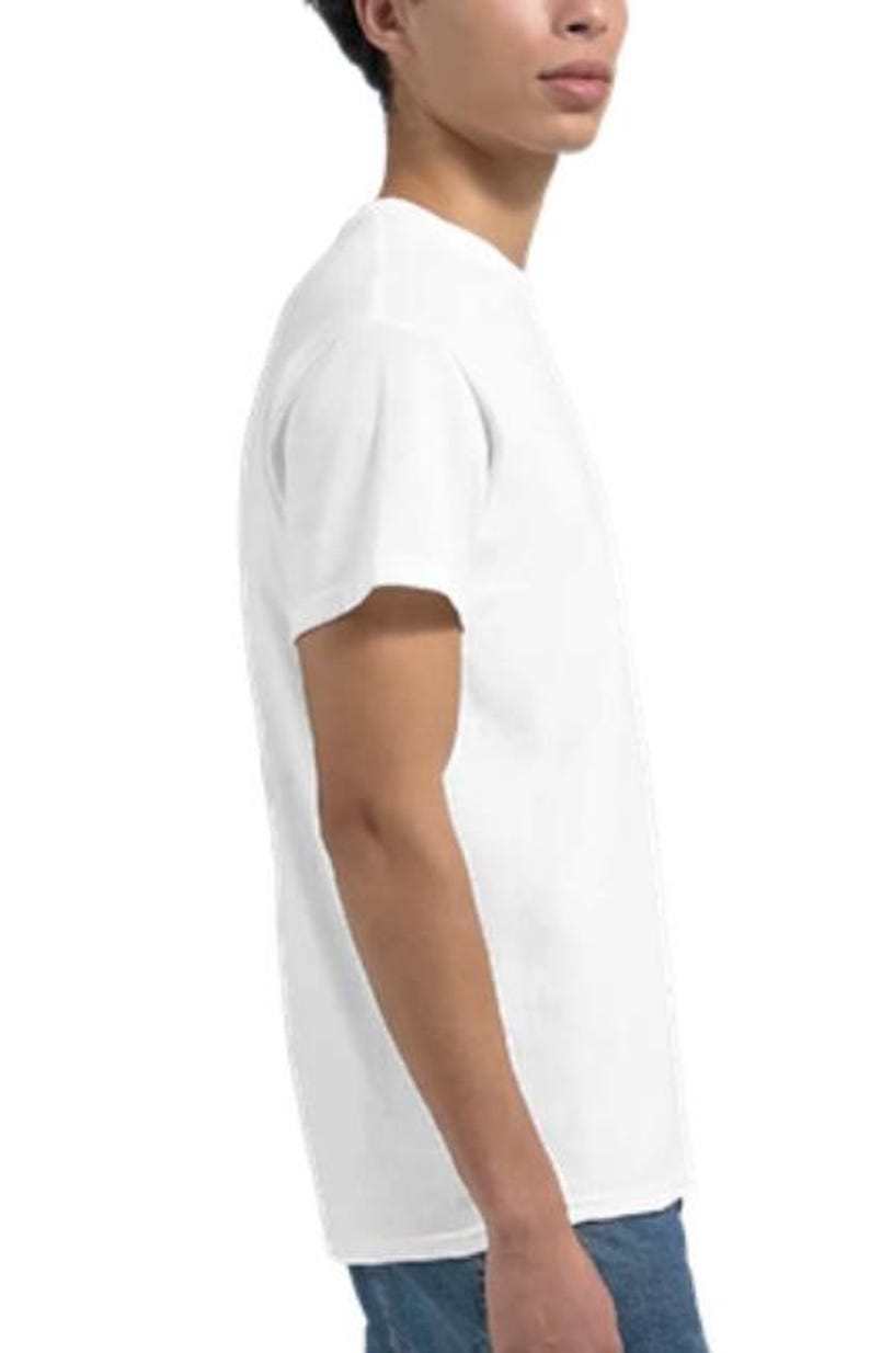 May include: A plain white t-shirt with short sleeves. The shirt is made of a soft material and is being worn by a person. The person is wearing blue jeans. The shirt is a basic, versatile garment.