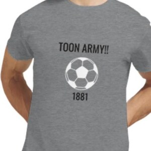 May include: Grey crew neck t-shirt featuring the text "TOON ARMY!!" above a white and black football graphic and the number "1881" below. The shirt is made of a soft material.