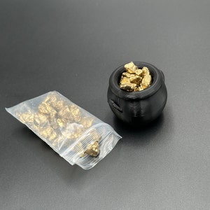 May include: A black pot filled with gold nuggets, and a plastic bag filled with gold nuggets.