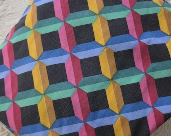 May include: A square fabric cushion featuring a repeating geometric pattern of black squares surrounded by three-dimensional blocks in shades of yellow, pink, blue, and green, creating an optical illusion of depth across the entire surface.