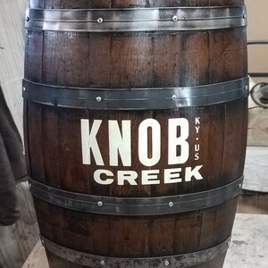 May include: A brown wooden barrel with metal bands and the words "Knob Creek KY. US" printed on the side.