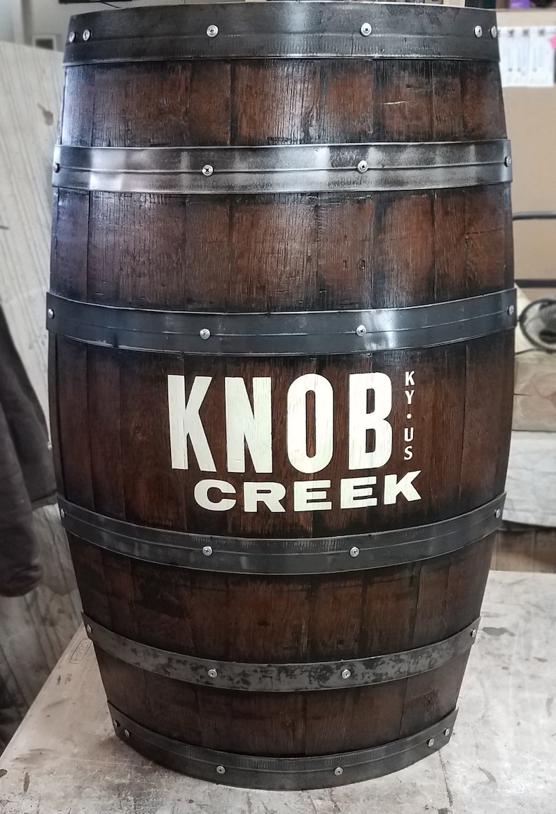 May include: A brown wooden barrel with metal bands and the words "Knob Creek KY. US" printed on the side.