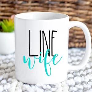 May include: White ceramic coffee mug with a black and turquoise design. The mug has a handle and says "LINE wife" in black and turquoise lettering.