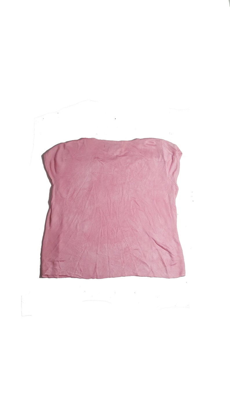 May include: A pink short-sleeved shirt made of a soft, textured fabric.
