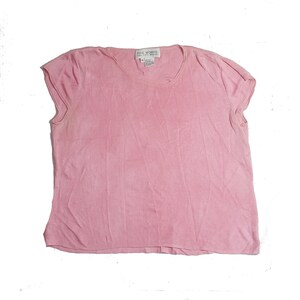May include: A pink short-sleeved knit top with a scoop neck. The label reads "The Works Easy Fit Apparel".
